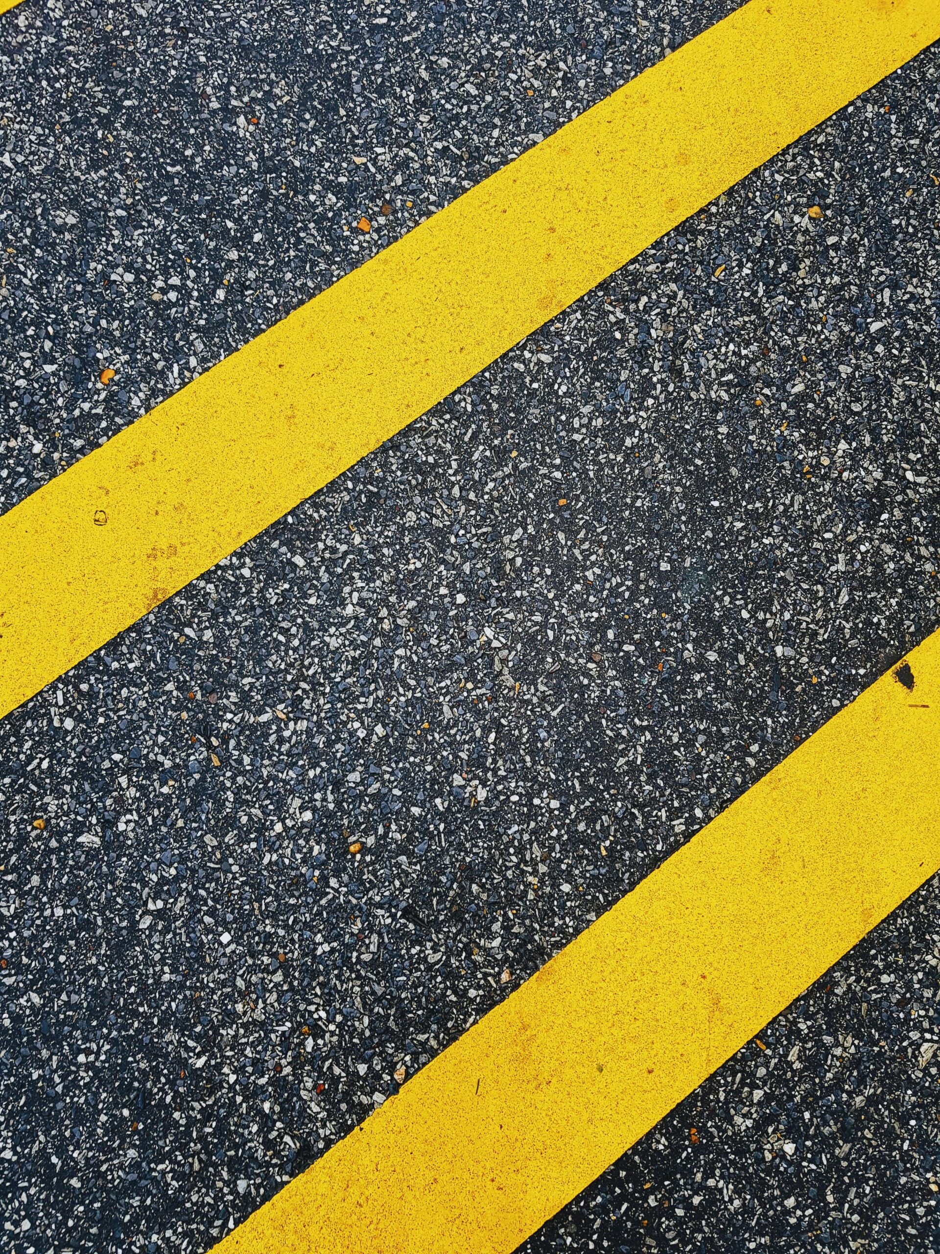 Close-up of vivid yellow road markings on textured asphalt surface.